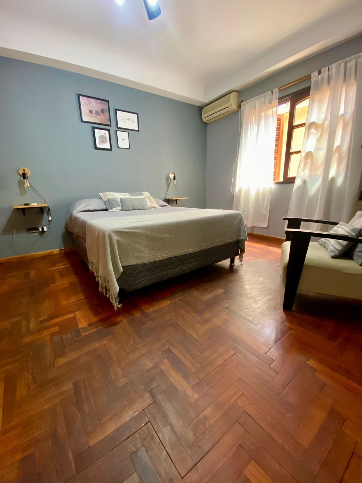 Une chambre à coucher comprenant un lit, une chaise, un bureau et un climatiseur fixé au mur.