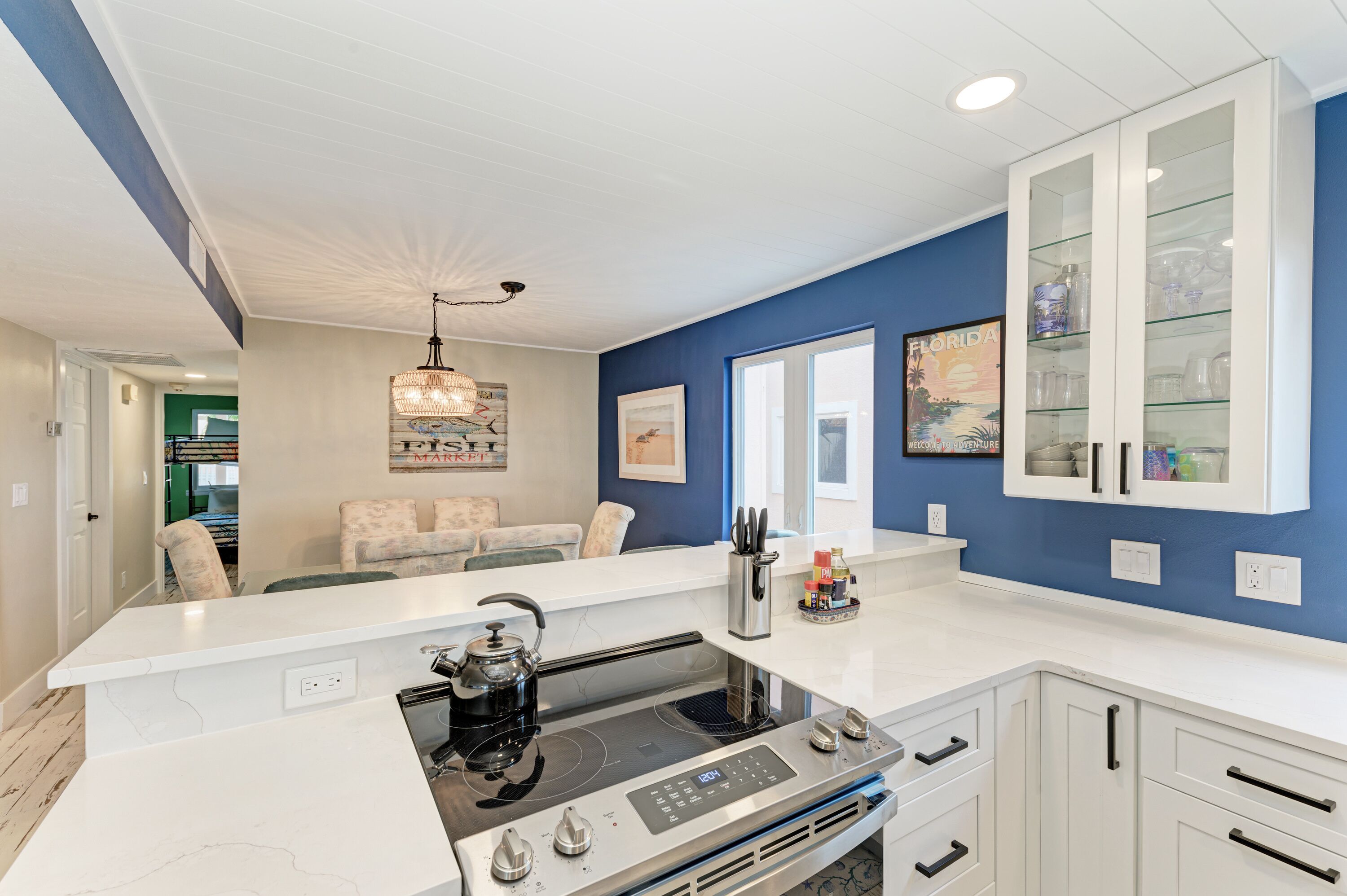 A modern kitchen with white cabinetry, a built-in stove, and a large island.