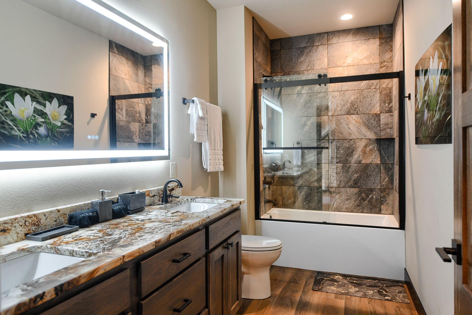 A modern bathroom with a marble countertop, a glass-enclosed shower, and a toilet.