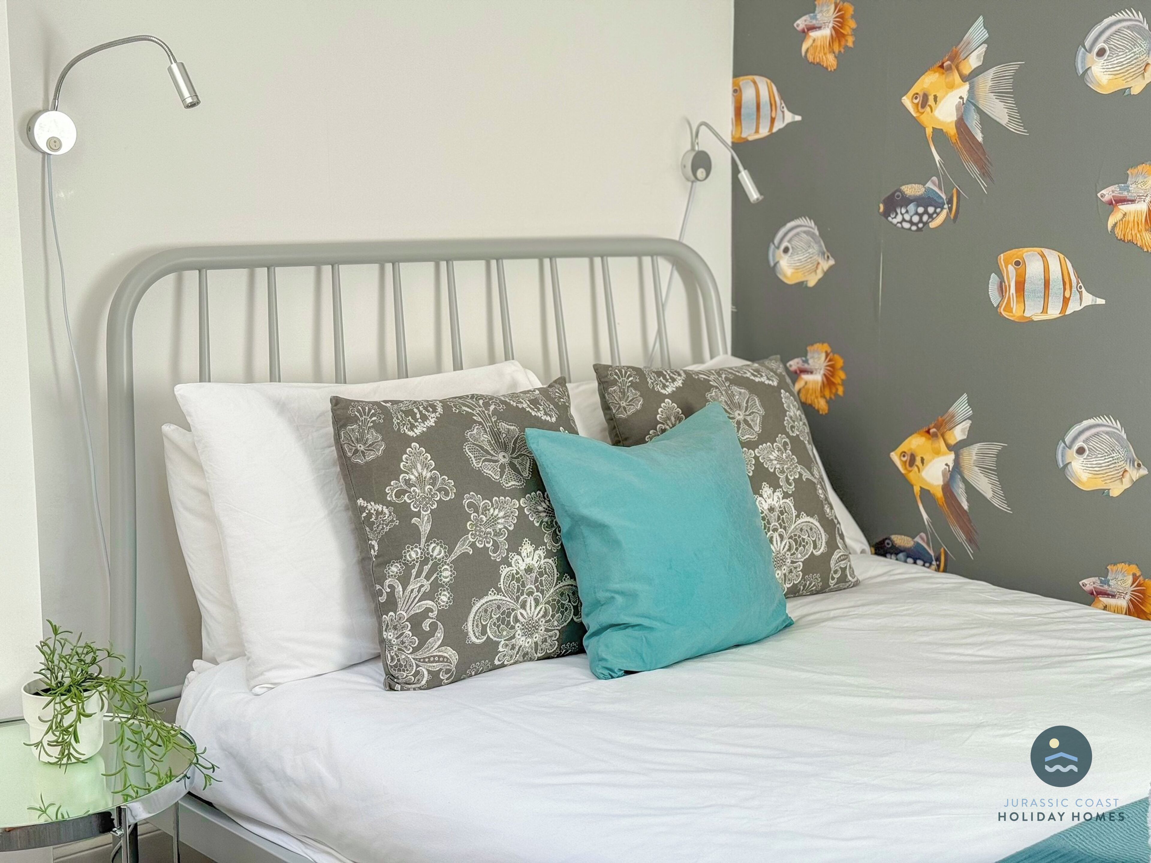 A bed with white bedding, a grey headboard, and patterned pillows.