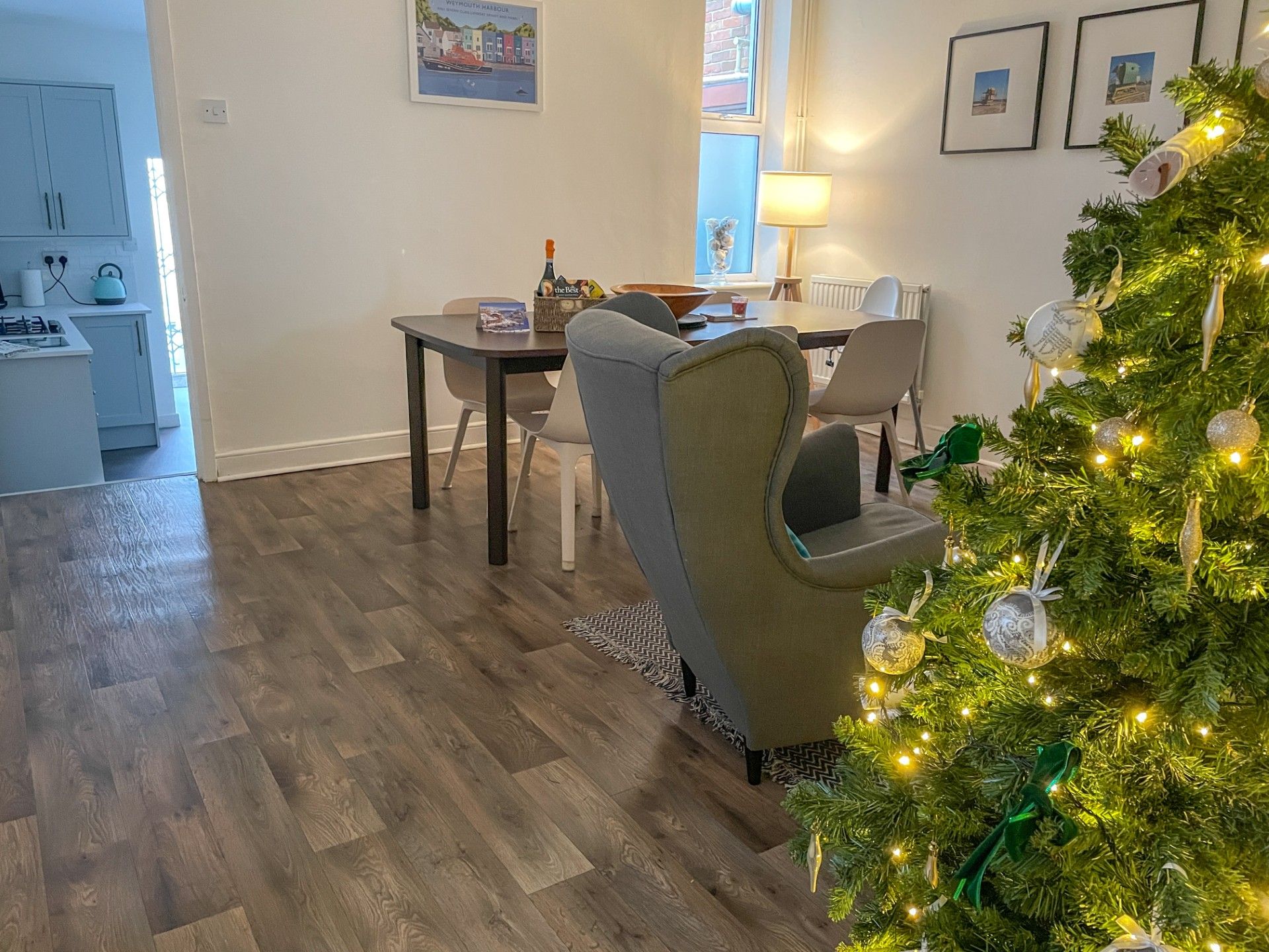 A modern kitchen with a dining area, a Christmas tree, and a view of the outside.
