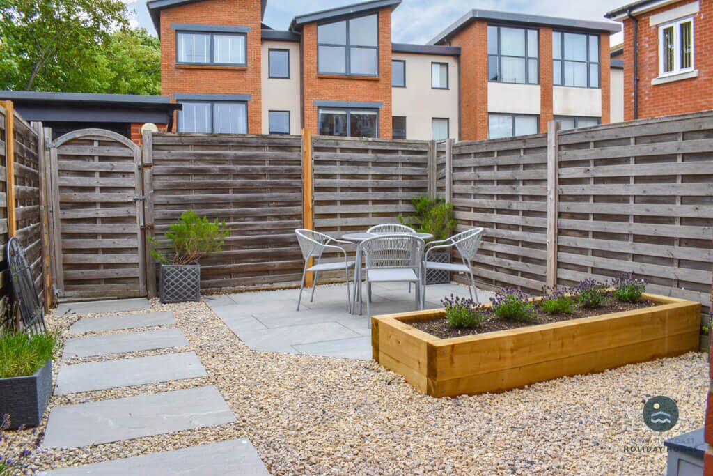 Un espace patio agrémenté d’une clôture en bois, d’un coin salon et d’un parterre surélevé.