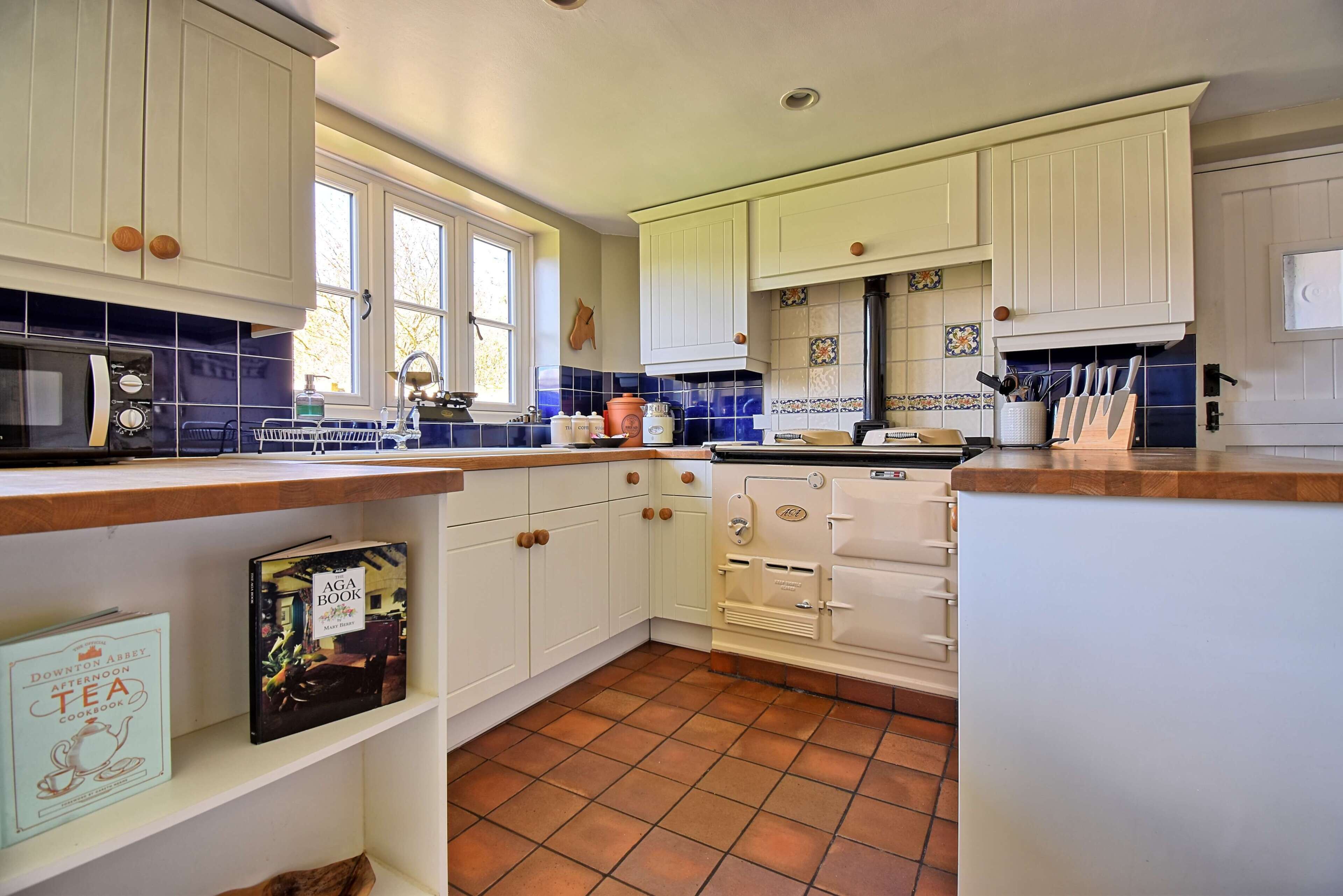 A kitchen with white cabinets, a stove, and a window.