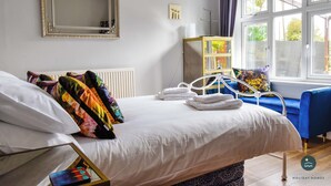 Une chambre d’hôtel avec un lit, un miroir, une fenêtre et une chaise bleue.