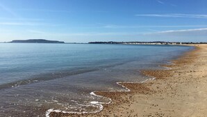 A beach with clear water, pebbles, and a distant hill. - Pebble House - Sea views, parking, family friendly (Weymouth)