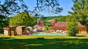 Un jardin avec une piscine, des chaises longues et un petit abri en bois.