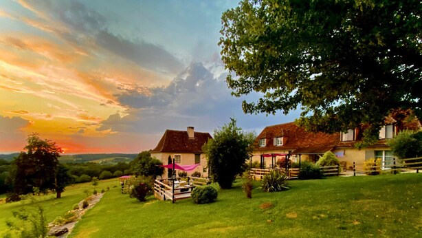 Une propriété située à la campagne, comprenant deux maisons, un grand arbre et un champ d’herbe.