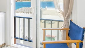 A room with a sliding glass door leading to a balcony with a view of the sea.