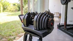 A home gym with a set of adjustable dumbbells on a rack, a barbell, and a weight bench. - Les Hauts d'Avignon - Guesthouse - Room 1 (Rochefort-du-Gard)