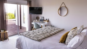 A bedroom with a bed, a desk, a TV, and a view through a sliding door. - Les Hauts d'Avignon - Guesthouse - Room 1 (Rochefort-du-Gard)