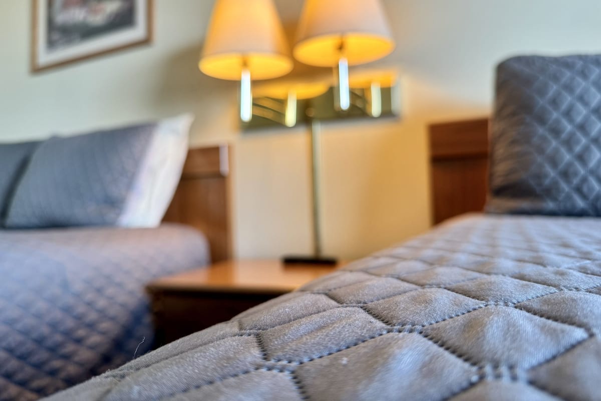 A hotel room with a bed, two bedside lamps, and a nightstand.