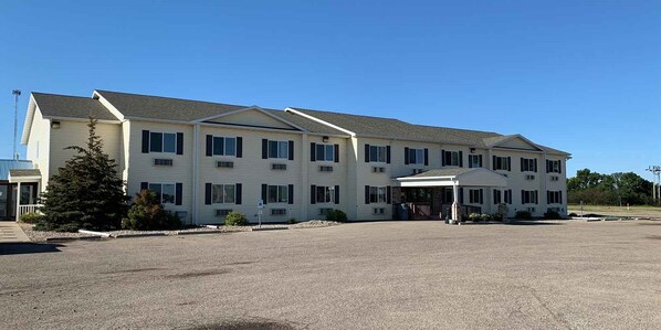 A multi-story hotel with a covered entrance and a parking lot in front.