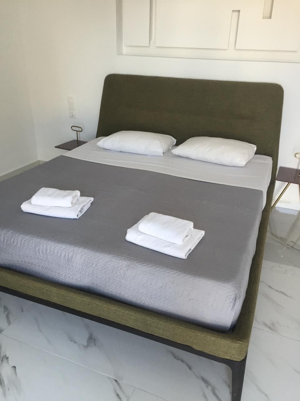 A neatly made bed with two pillows and two folded towels.