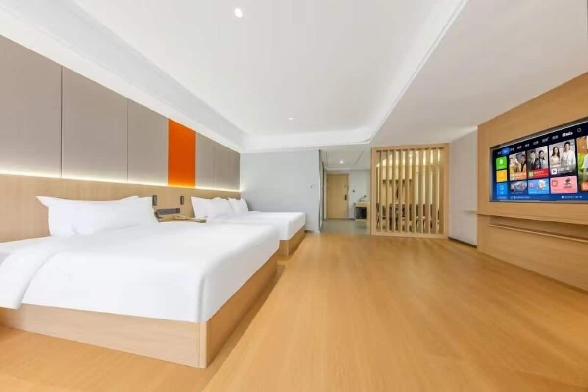 A modern hotel room with a large bed, a TV, and a wooden floor.