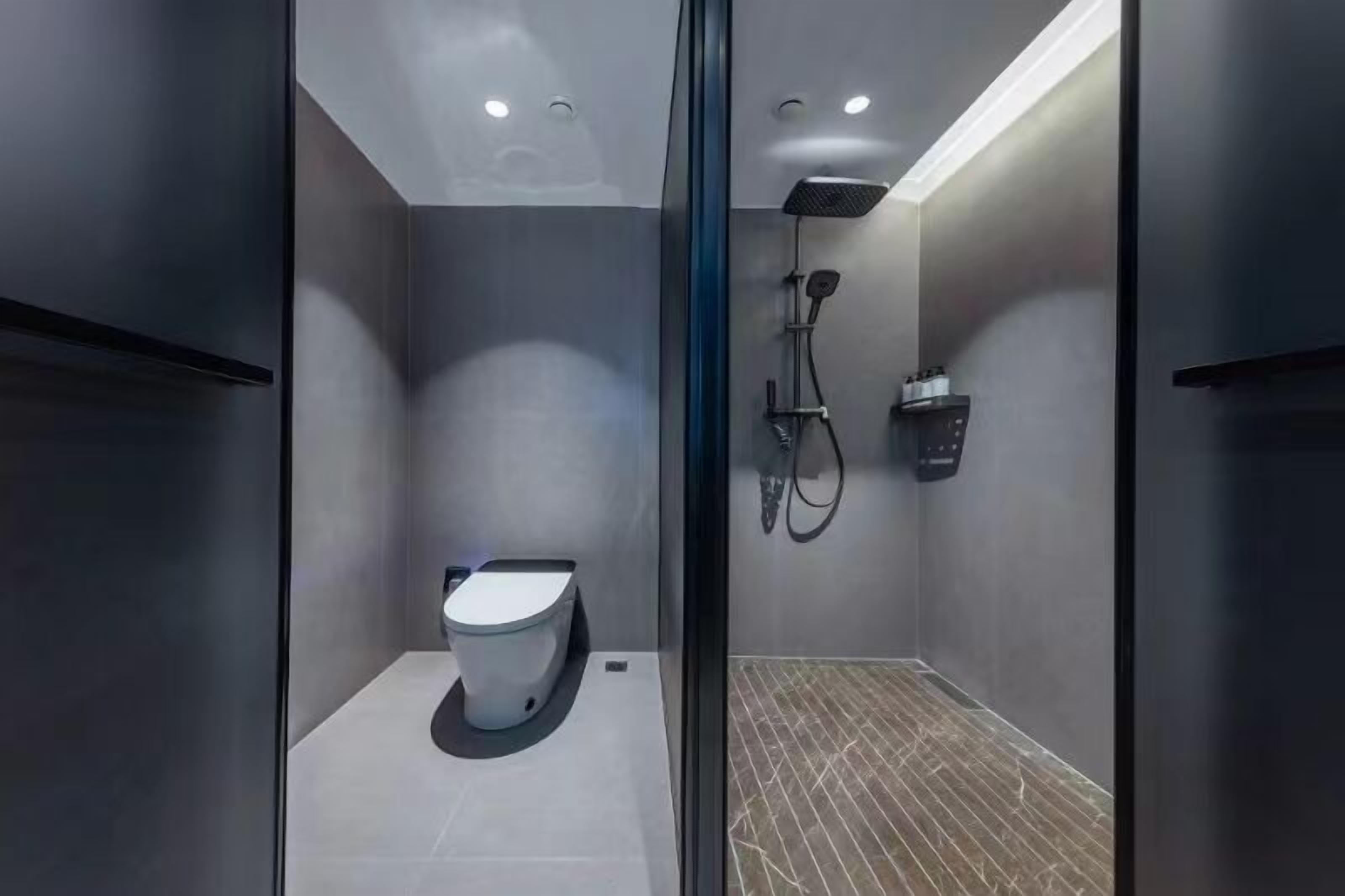 A modern bathroom with a toilet, shower, and a glass partition.