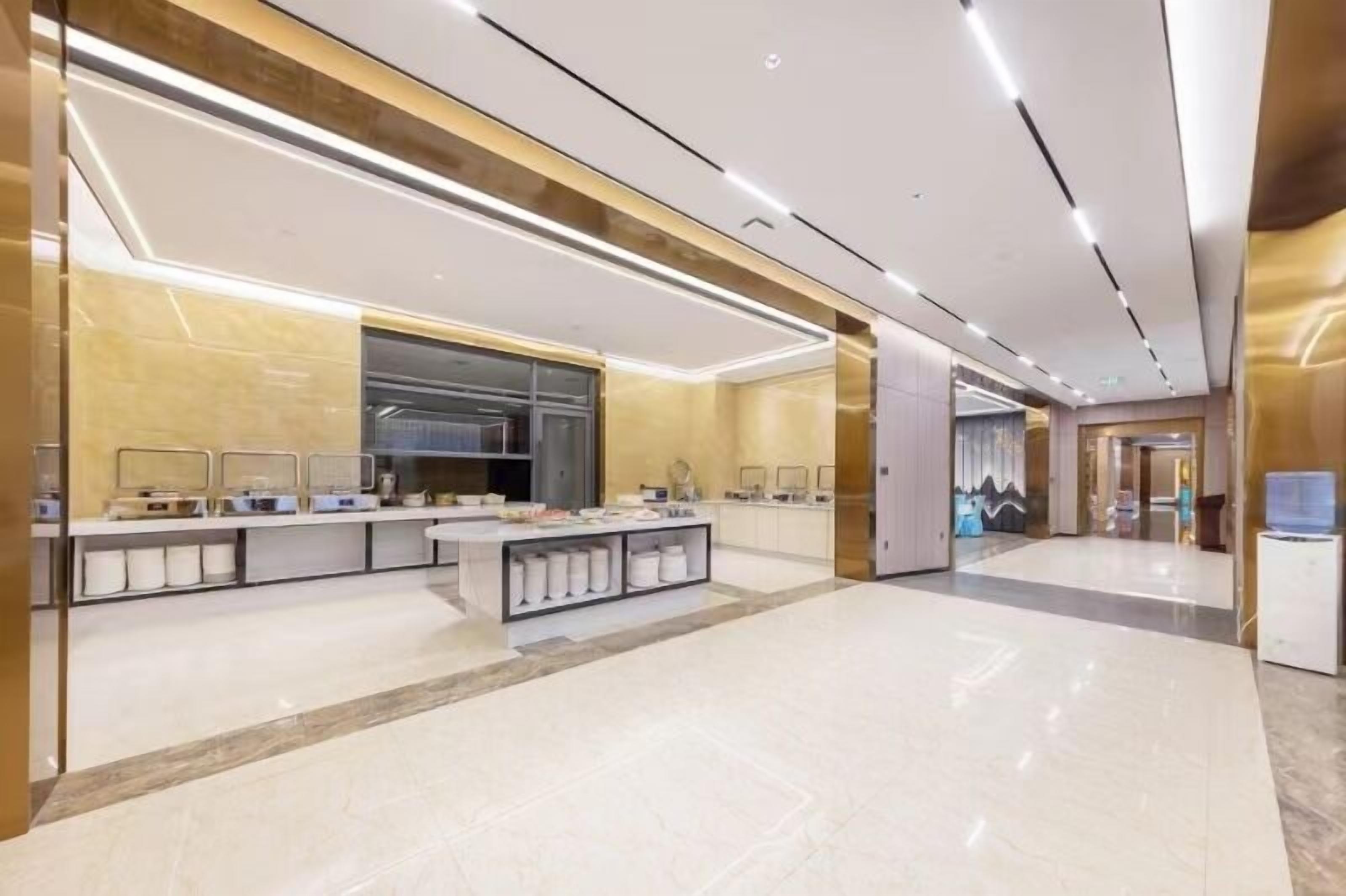 A modern hotel lobby with a central reception desk, a large mirror, and a sleek, minimalist design.