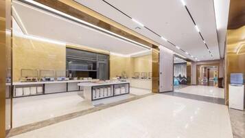 A modern hotel lobby with a central reception desk, a large mirror, and a sleek, minimalist design.