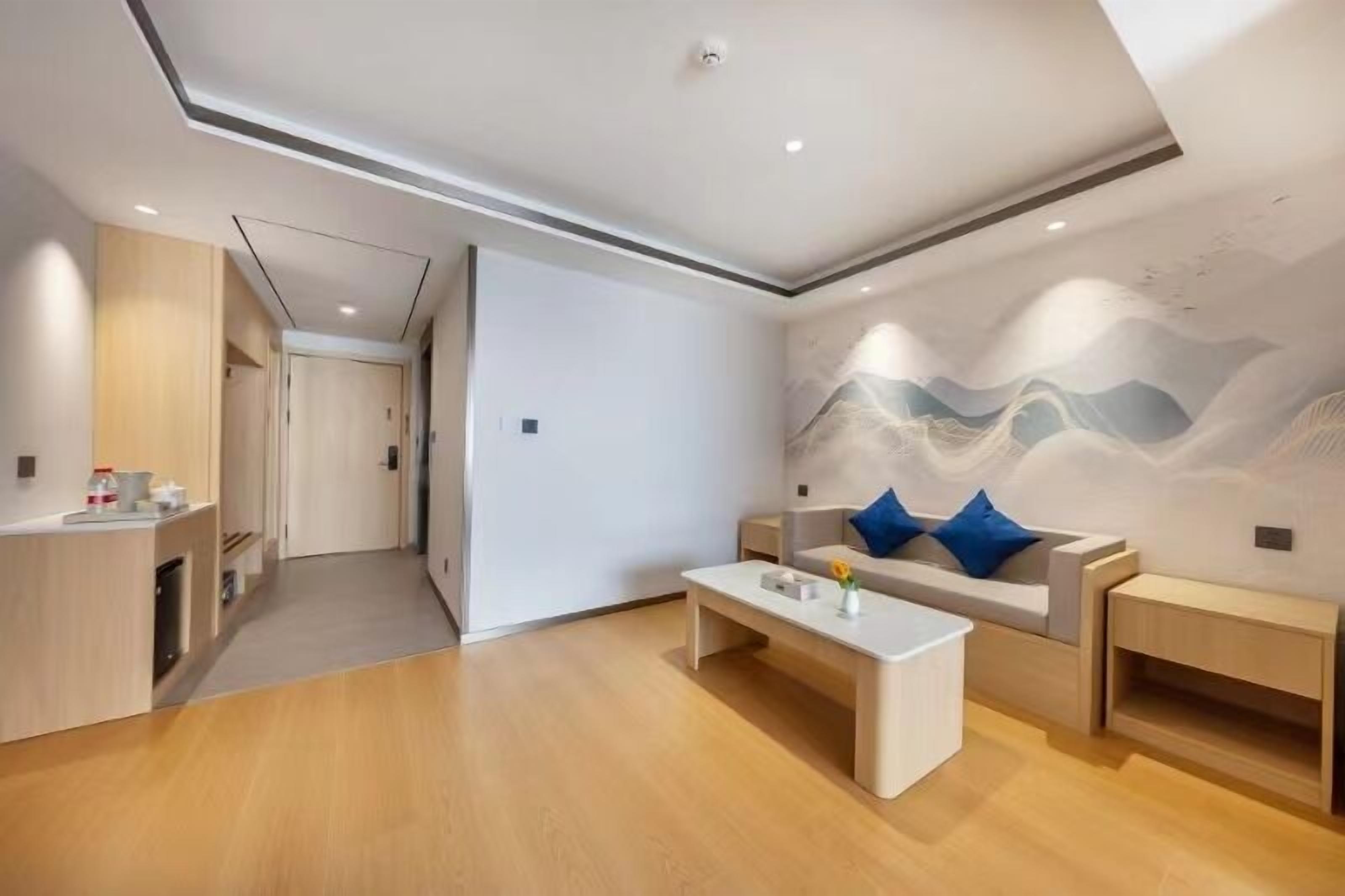 A modern living room with a sofa, coffee table, and a wall with a mountain mural.