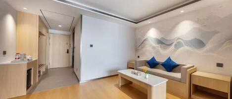Un salon moderne avec un canapé, une table basse et un mur orné d’une fresque représentant une montagne.