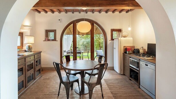 Cocina y comedor integrados con techo de madera, ventanas amplias y vistas al exterior.