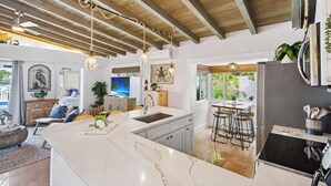 Una cucina moderna con una grande isola, elettrodomestici integrati e un soffitto rustico.