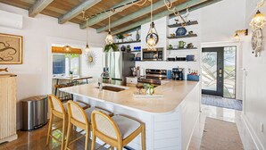 Cucina spaziosa con un'isola grande, sedie in legno e illuminazione a sospensione.