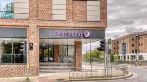 A Premier Inn hotel with a brick facade, large windows, and a visible entrance with steps.