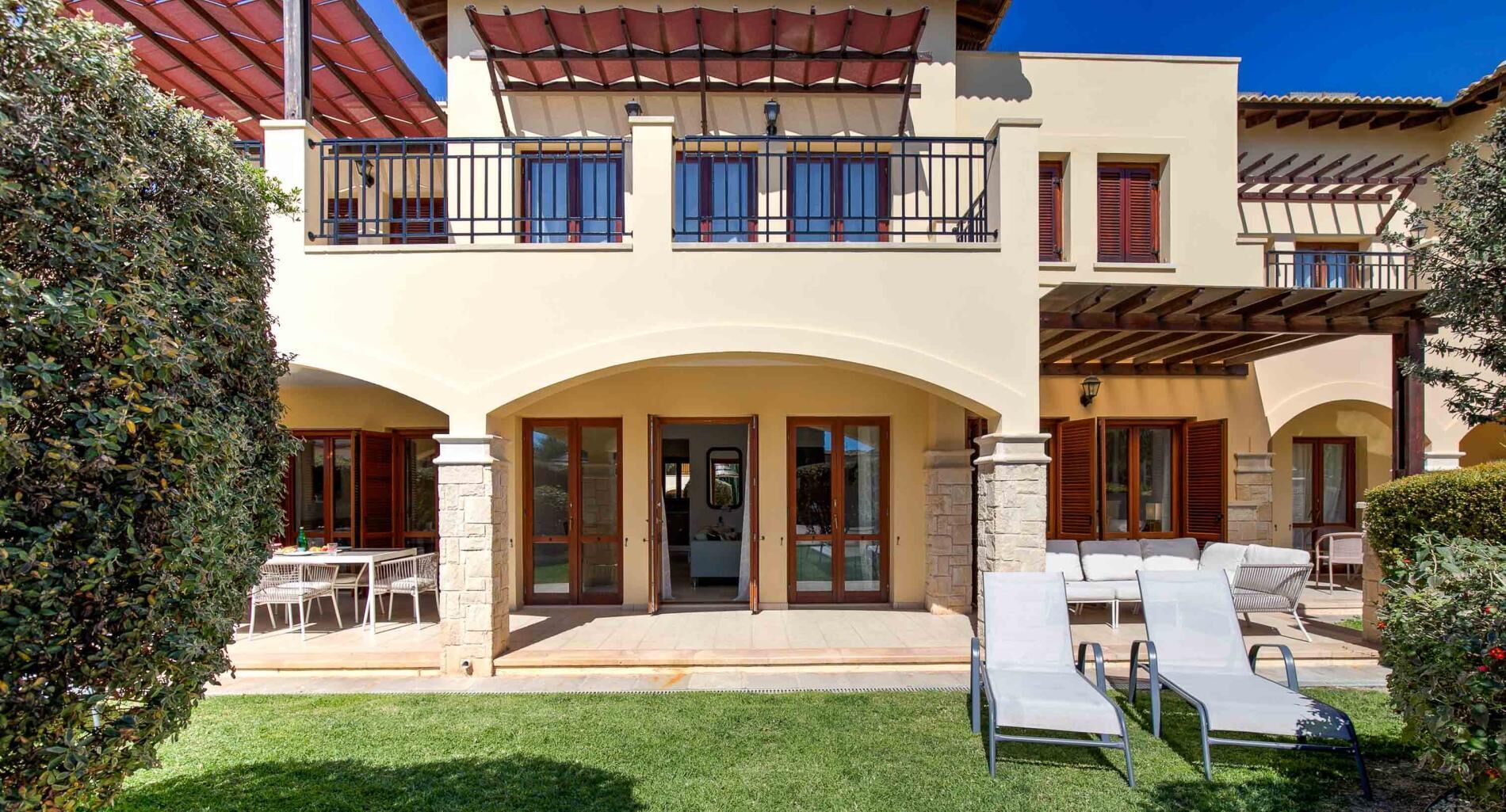 A two-story building with a covered patio, outdoor seating, and a well-maintained lawn.
