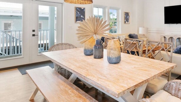A dining area with a wooden table, wicker chairs, and a bench. There are decorative vases on the table. - Stay @ Jasper Jetty - 8 bedrooms, 2 pools! (Folly Beach)
