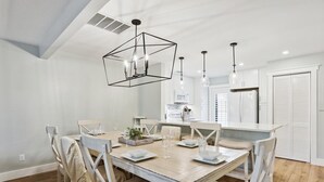 Ein Essbereich mit einem Holztisch, weißen Stühlen und Pendelleuchten.