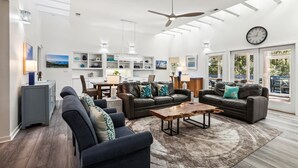 A spacious living room with a ceiling fan, a dining area, and a view through large windows. - Single Level Vacation Home w/ Private Pool (Hilton Head Island)