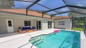 Une piscine extérieure couverte, dotée d’un espace salon intégré, avec une maison en arrière-plan.