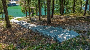 Una escalera de piedra que desciende hacia un cuerpo de agua, rodeada de árboles.