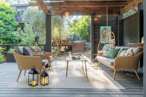 Un patio al aire libre con mobiliario de mimbre, faroles y un columpio colgante.