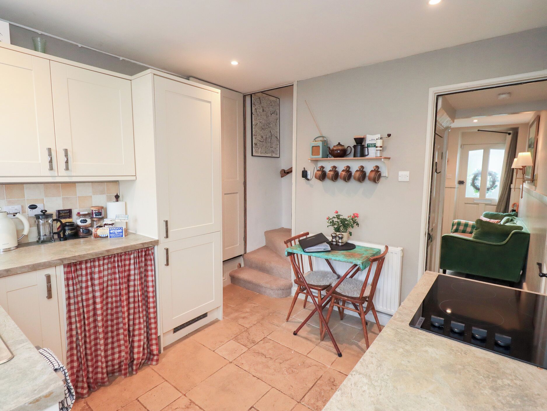 A compact kitchen with white cabinets, a dining table with chairs, a small stove, and a window with curtains.