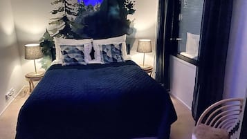 Un dormitori amb un llit, dues làmpades de nit, una finestra i una cadira.