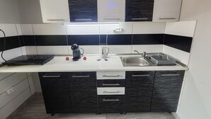 A compact kitchen with a built-in stove, a kettle, a sink, and a microwave.