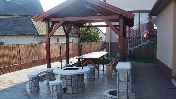 An outdoor patio with stone seating, a wooden pergola, and a fire pit.
