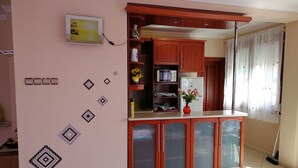A kitchen with wooden cabinets, a microwave, and a refrigerator. There is a vase with flowers on the counter.