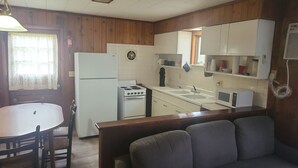 Cocina compacta con electrodomésticos básicos, una mesa y un banco.