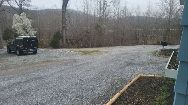 A gravel driveway leading to a building with a mailbox and a bird feeder.