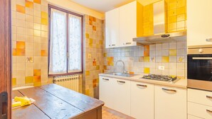 Une cuisine de taille réduite, dotée d’une fenêtre, d’un radiateur, d’un évier, d’une cuisinière et de placards.