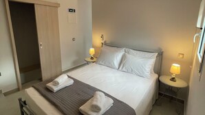 Una habitación de hotel con cama, mesitas de noche, lámpara, equipo de aire acondicionado y una puerta.