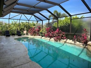 Relax by the pool surrounded by lush greenery and palm trees.