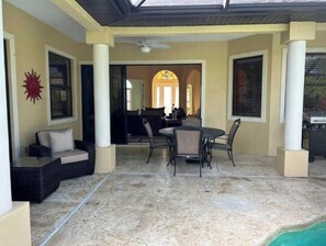 Relax in this serene outdoor space with a dining table, sofa, and grill, perfect for al fresco dining and socializing.