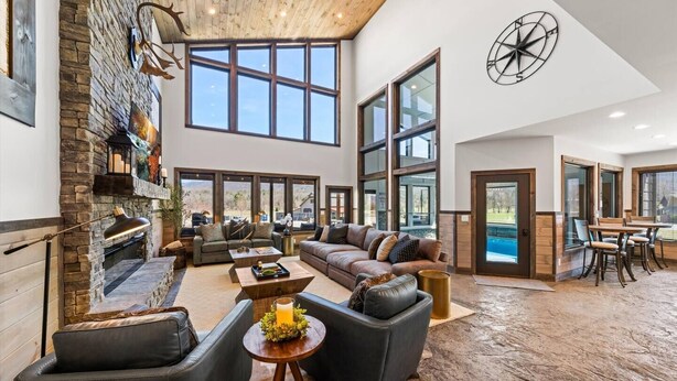 A spacious living area with a fireplace, large windows, and a pool view.