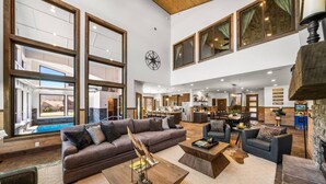 A spacious living area with a large sofa, coffee table, and a view of a pool and outdoor space.