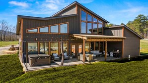 A modern two-story house with large windows, a covered patio, and outdoor furniture.
