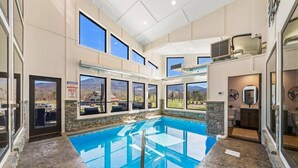 A spacious indoor swimming pool with a clear view of the surrounding landscape through large windows.