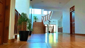 Un hall d’entrée spacieux avec un escalier en bois, des plantes en pot et une vue sur le deuxième étage.